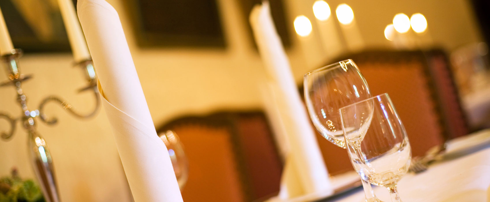 A pair of wine glasses on a table with candles