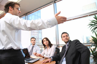 A man gesturing to something with a few others looking on.