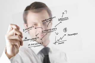 A man writing business plan ideas on a glass pane.